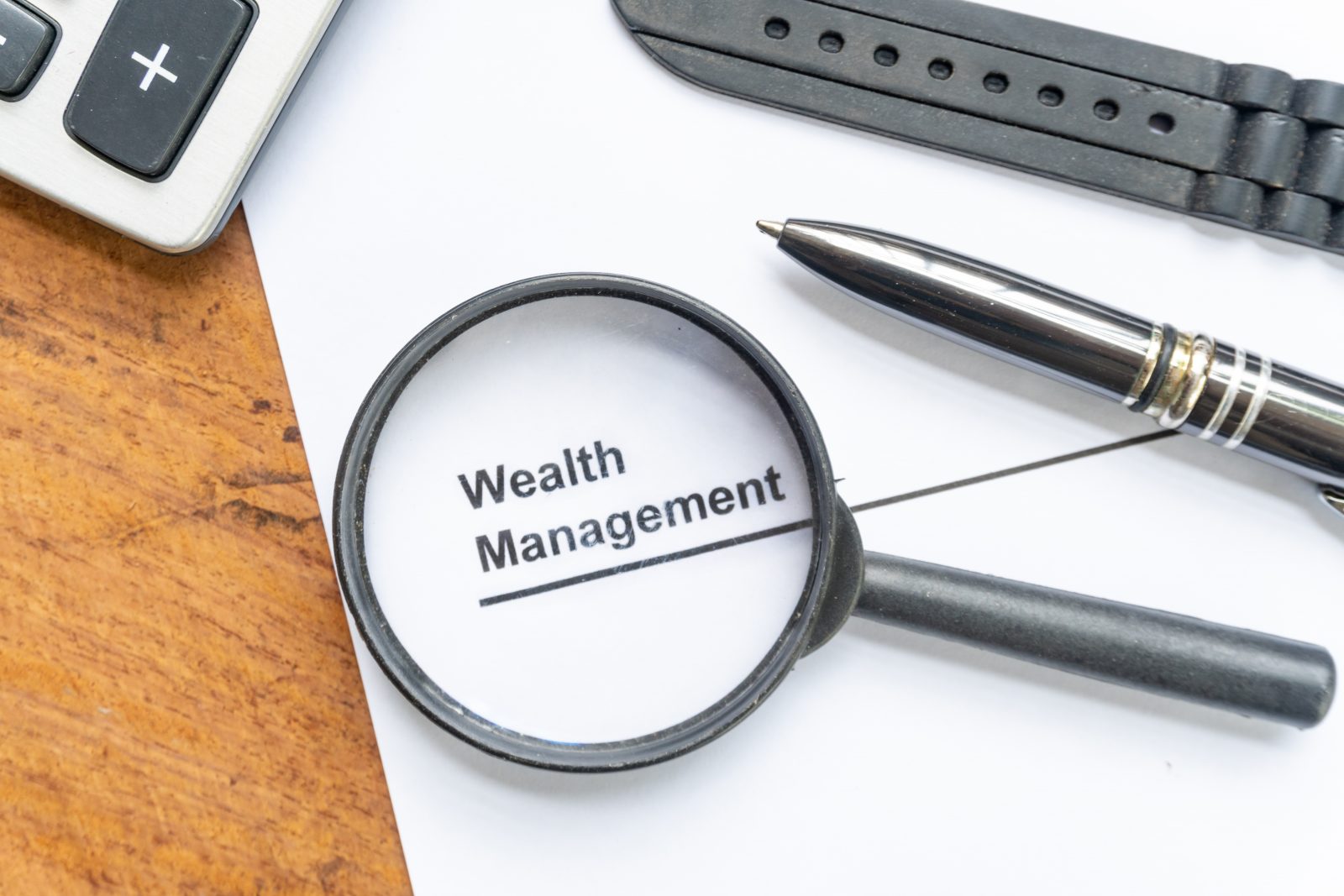 magnifying glass highlighting words "wealth management' typed on a paper
