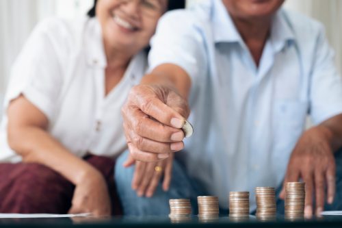 Retirement saving planning. Happy senior couple holding a coin to arrange in a row.